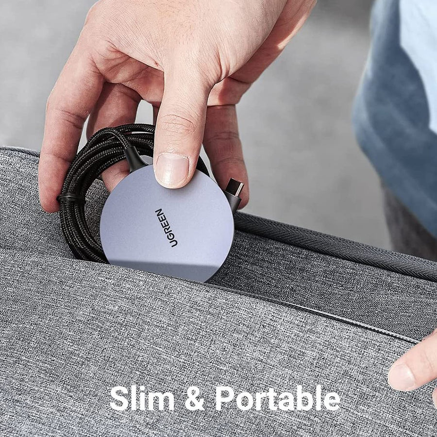 Hand tucking the Ugreen 30233 charger and its coiled cable into a grey bag pocket